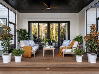Coastal cottage vibes infuse the back deck at HGTV Smart Home 2022 including this inviting seating area. Matching outdoor sofas provide ample seating space while potted plants add life and color.
