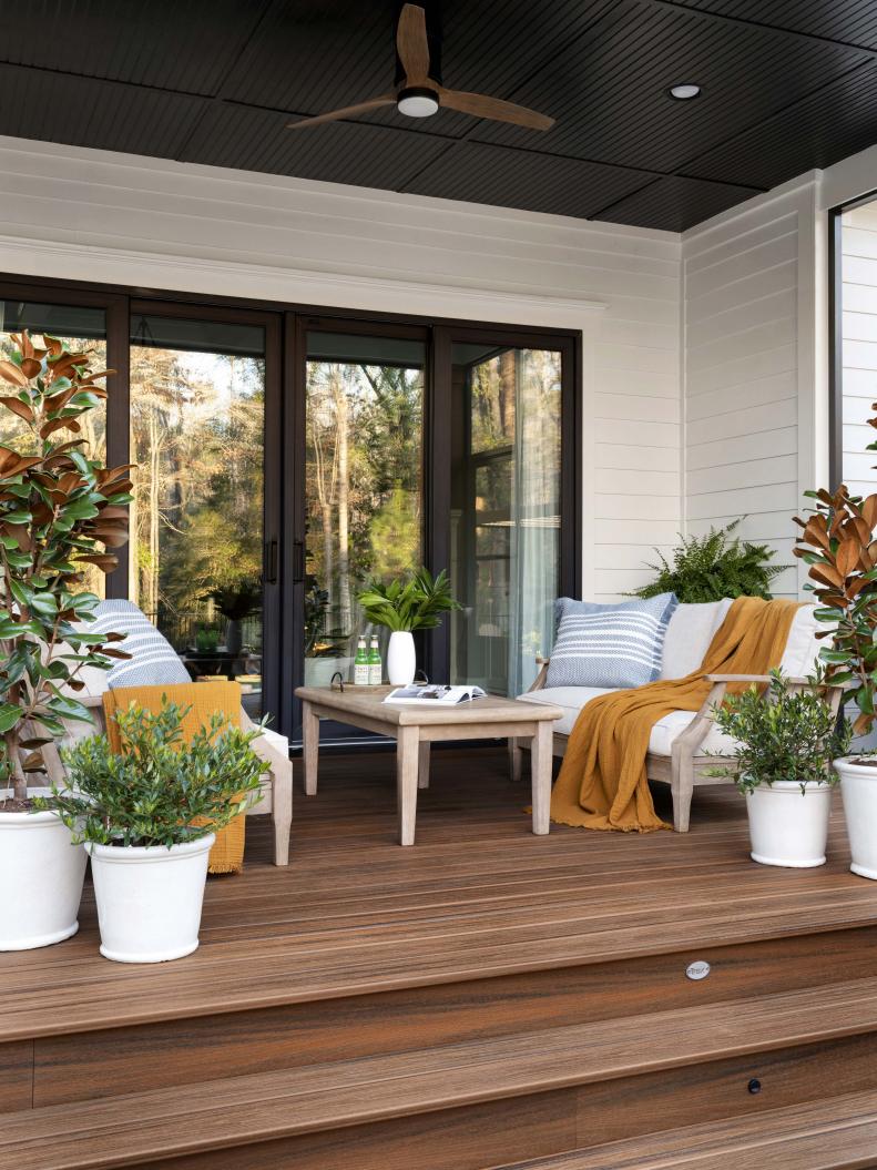 Steps fabricated in all-weather decking lead down from the seating area to the backyard and outdoor pool space. The home’s white exterior and black accents play off the wood decking for a classic and naturally beautiful feel.