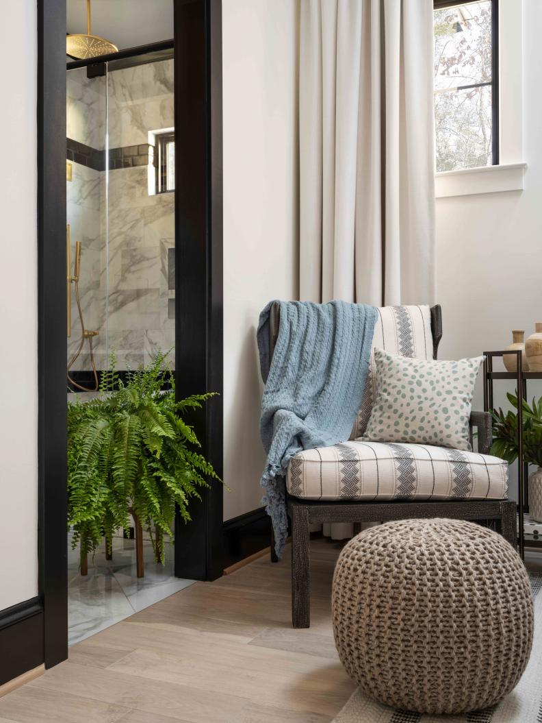 The accent chair sits by the arched opening that connects the main bedroom to the high-style main bathroom, with a spa-like wet room and connection to the organized main bedroom closet.