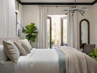 Glass doors open to an enticing seating area outside, giving this main bedroom an easy connection with the well-designed outdoor spaces that make HGTV Smart Home 2022 so appealing.