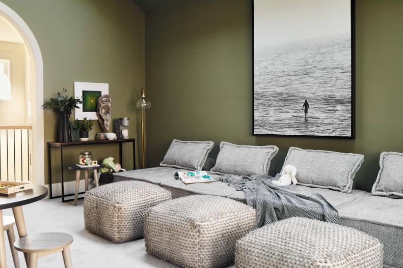 The walls in the playroom are painted a mellow shade of green that brings a soothing, organic feel to the room. Matching pillows and ottoman poufs create a lounge space for the entire family to gather and connect or just unwind with a favorite book