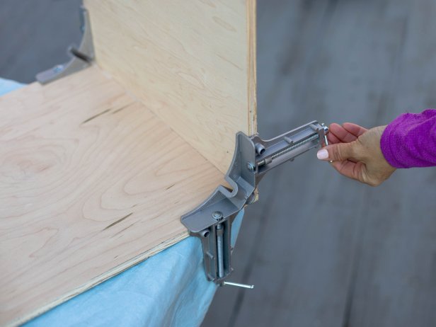Use right-angle clamps to hold the bottom piece and one of the side pieces together. Add wood glue to the seam before you tighten everything up.
