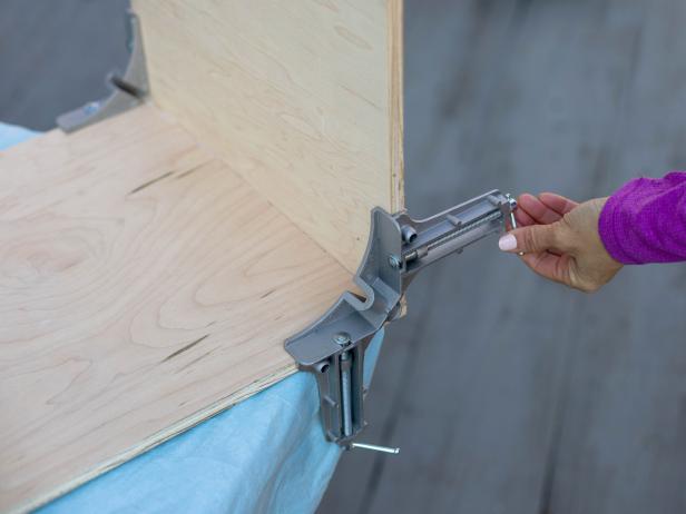 Use right-angle clamps to hold the bottom piece and one of the side pieces together. Add wood glue to the seam before you tighten everything up.