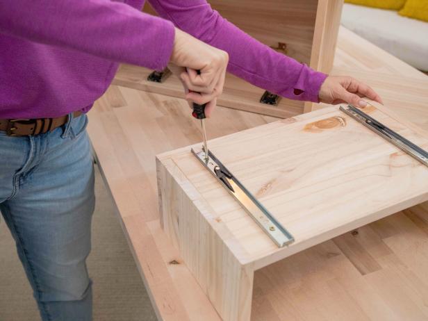 Separate the pieces of the drawer slides. Attach one piece to the bottom of the drawer and the other piece to the base of the middle section of the unit.