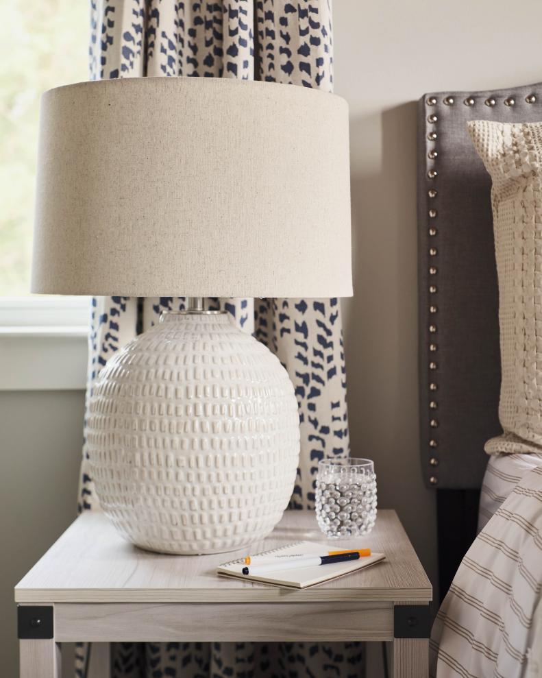 A textured white table lamp with a natural linen shade plays off the room’s organic textures and geometric patterns while adding a much-needed reading light after dark.