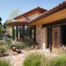 Mediterranean Residential Landscape Design With Airy Ornamental Grasses, Terracotta Roof, and Natural Stone Hardscape