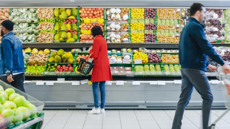 A woman chooses organic fruits in the fresh produce section of the store. 