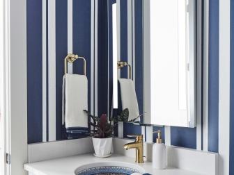With bold striped walls and user-friendly features, this powder room located on the first floor of HGTV Smart Home 2022 reflects the contemporary style of this sophisticated and timeless waterside retreat.