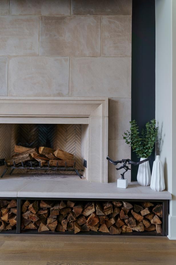 Pale stone fireplace with bench and stacked wood.