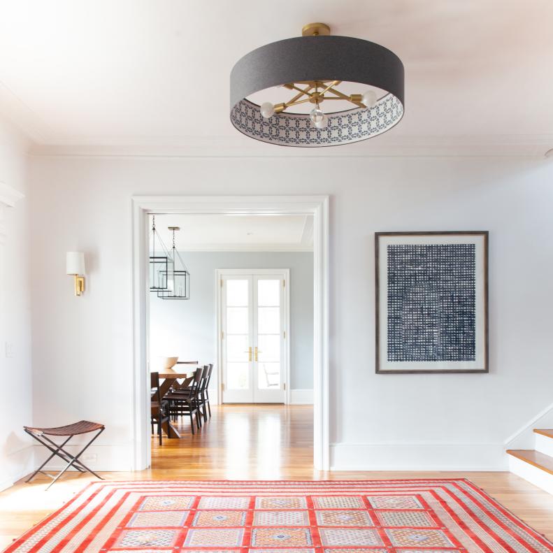 Bright white stair landing with black pendant and red area rug.