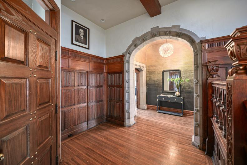 Wood-paneled hall with arched stone doorway. 