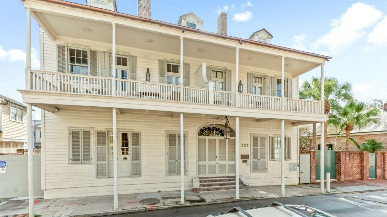 Three story white townhouse with pillars and second-floor balcony. 