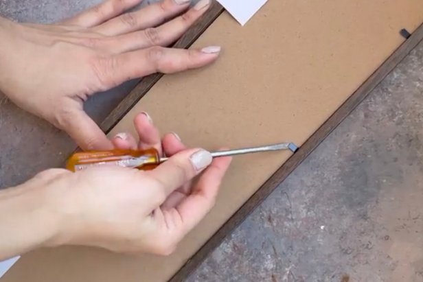 Remove the back of the welcome sign using a screwdriver.