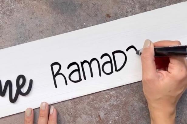 Use a black permanent marker to write the word Ramadan on the painted sign.
