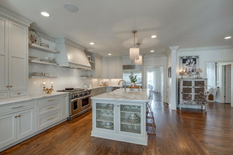 White kitchen with large marble-topped island and rustic details. 