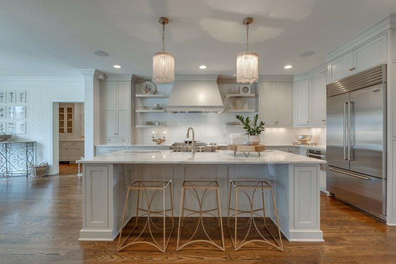White eat-in kitchen with wide island and elegant pendants.