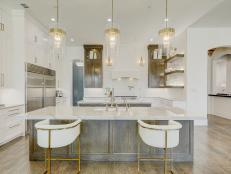 Gold and white kitchen with pendants and hardwood. 