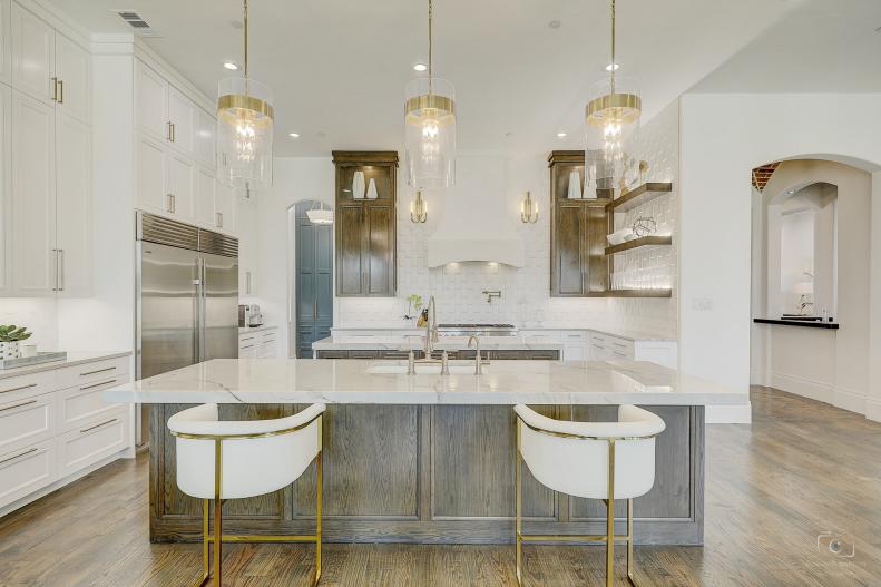 Gold and white kitchen with pendants and hardwood. 