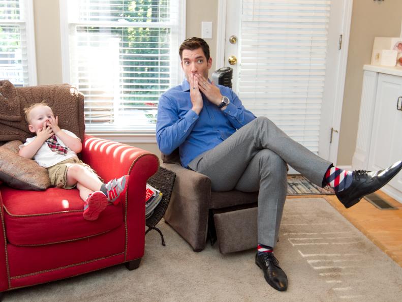Host Drew Scott sits in a kids' recliner next to Boyce Hunt while visiting the Hunt family in their current home prior to renovating and putting the house on the market, as seen on Property Brothers: Buying & Selling. Host Jonathan Scott renovates the family's current home for a successful sale, while Drew Scott oversees the selling of the renovated home and the buying of a new house. (action)