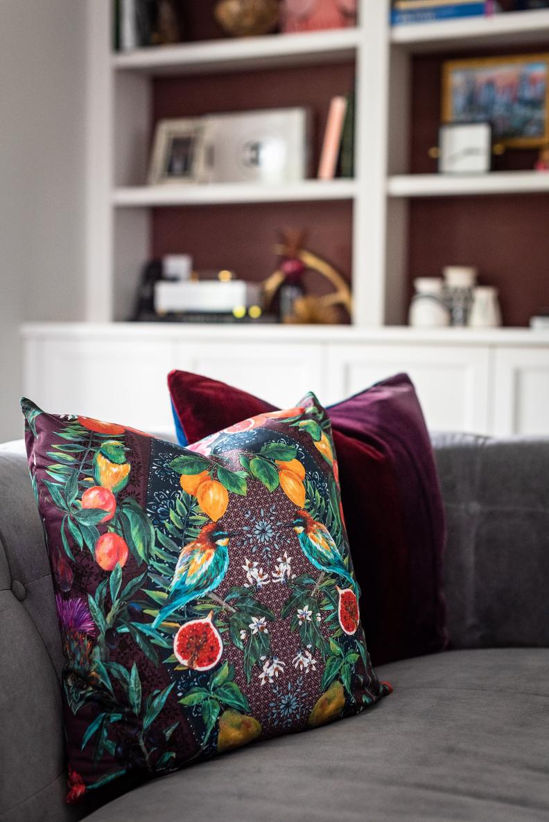 Bright botanical-print pillow on grey sofa. 
