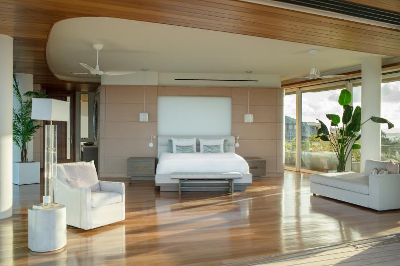 Wide bedroom with hardwood floor and white furniture. 
