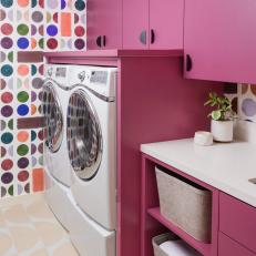 Colorful Laundry Room With Pink Cabinetry and Patterned Wall