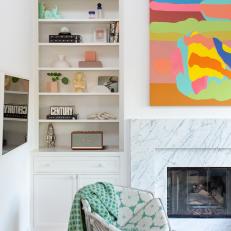 Colorful Artwork Hangs Over the Marble Hearth in this Living Room