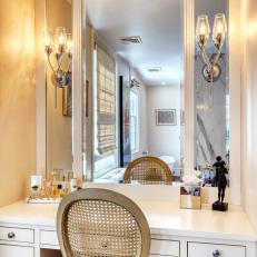 White Farmhouse Bathroom Vanity With Silver Sconces and Antique Chair