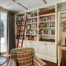 Historic White and Green Farmhouse Library With Cozy Armchair