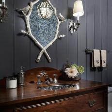 Black Bathroom Features a Wood Vanity and an Eclectic Mirror