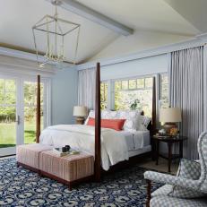 Bright Bedroom Features a Four Poster Bed and a Patterned Blue Rug