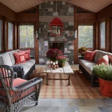 Rustic Screened Porch With a Stone Fireplace and Small Sitting Area