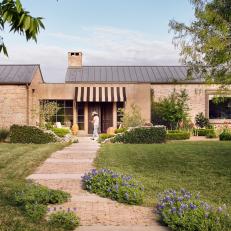A Rustic Brick Home Features a Striped Awning and a Stone Walkway
