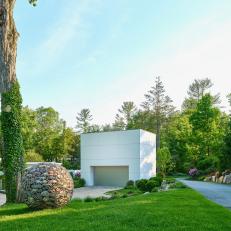 White, Modern Garage With Stone Sculpture and Gravel Driveway