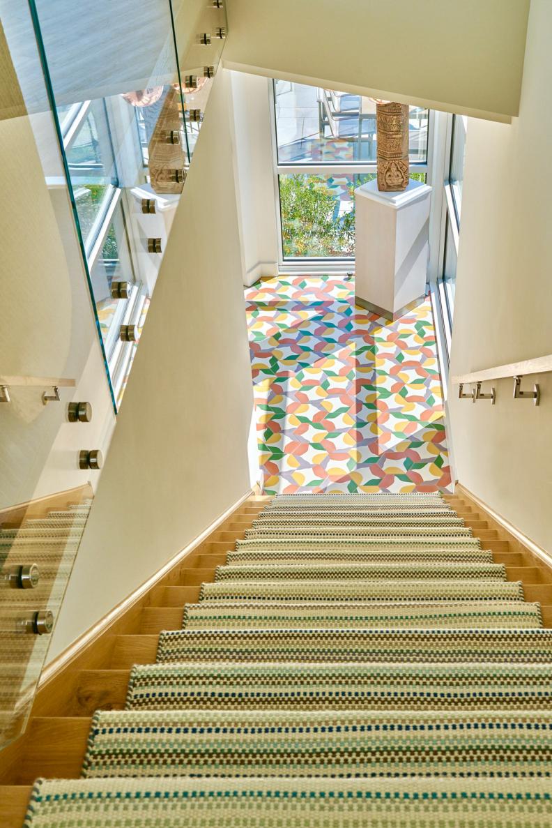 Staircase With Patterned Green Runner and Colorful Tile Landing