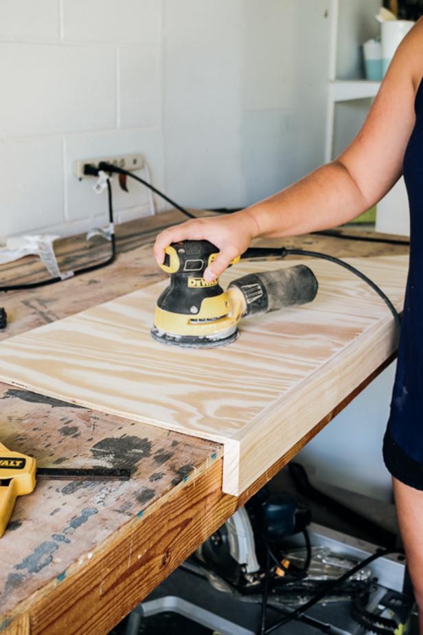 Woman sanding a piece of plywood