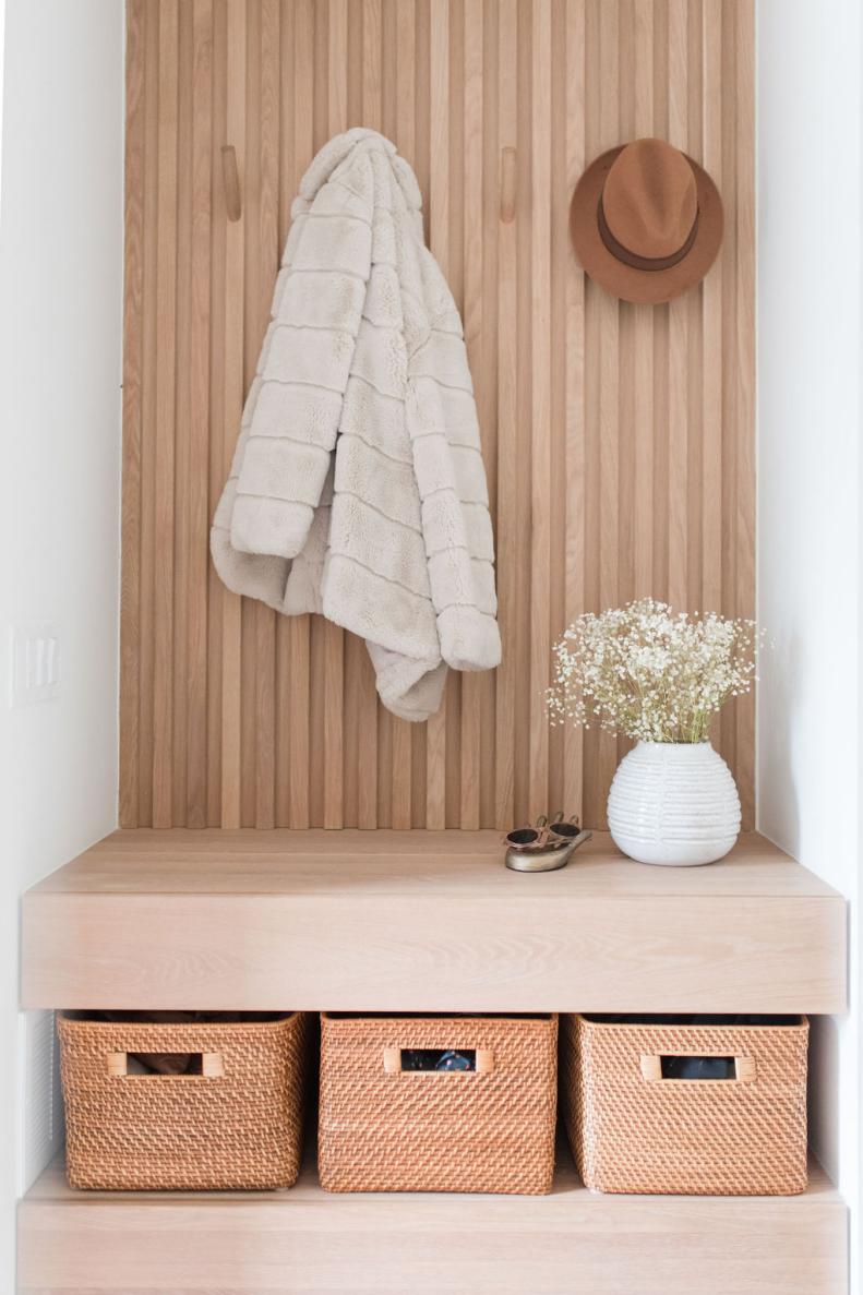 Tall white oak paneling with floating bench and woven cubbies. 