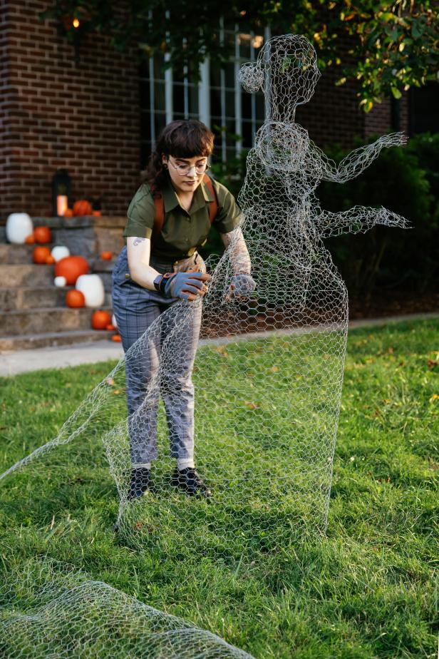 Chicken wire is bent and shaped to resemble a ghoulish figure with a long flowing skirt for a DIY Halloween decoration.