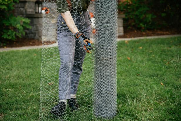 Wire cutters are used to remove a portion of chicken wire from a large roll. The piece is then used to create a DIY Halloween decoration.