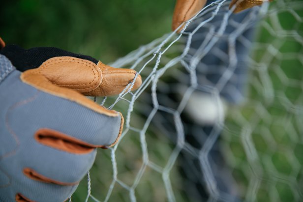 This roll of chicken wire is handled with gloves to protect the individual's hands.