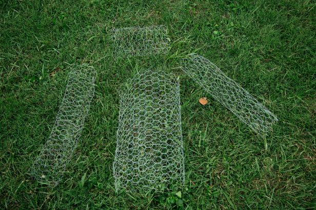 These rolls of chicken wire are laying on the grass awaiting assembly for a DIY Halloween decoration.