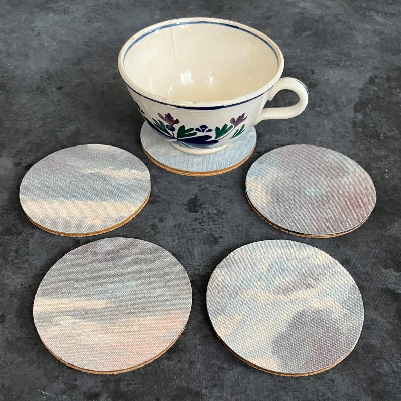 A teacup and five coasters covered in leftover Vapour - Dawn wallpaper.