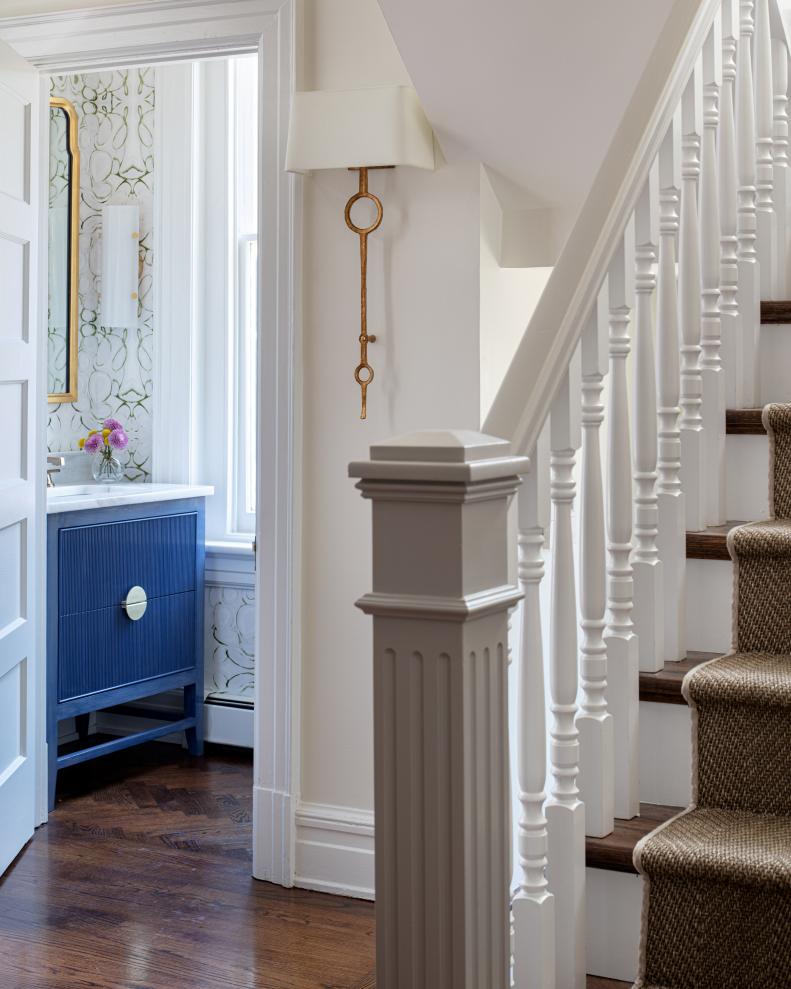 White foyer with slightly darker newel post and view of bathroom.
