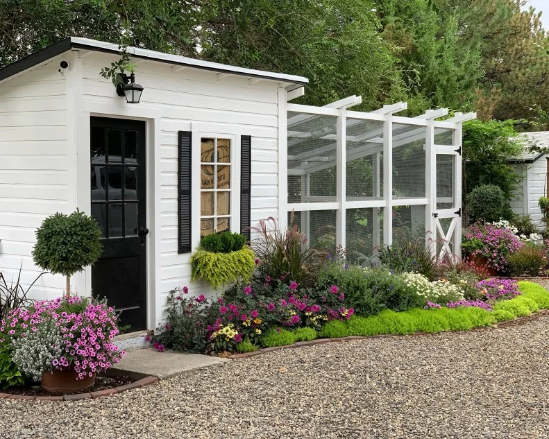 Landscaping Around a Shed A gravel path leading to a backyard shed landscaped with a border of flowers and foliage.