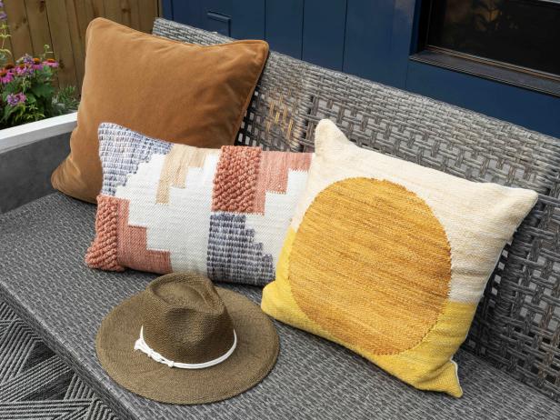 A mix of outdoor pillows in rust, burnt sienna, mustard and white add sunset tones to the backyard seating area.