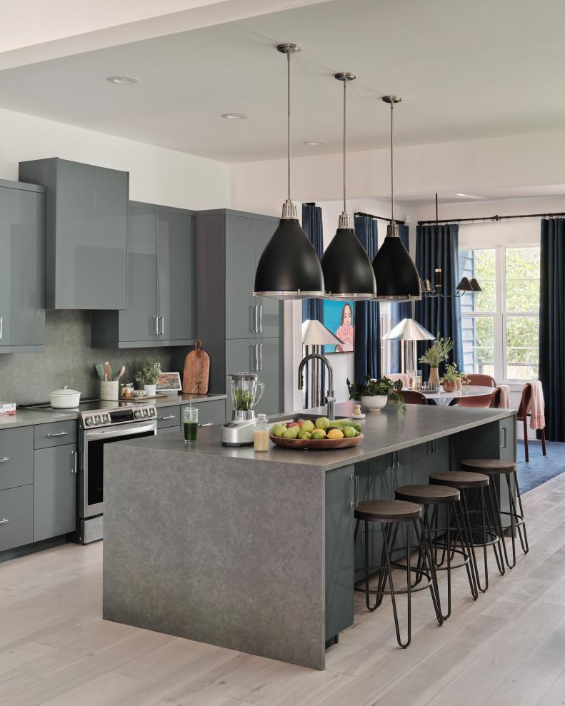 A trio of black, industrial style pendants anchor the space above the kitchen island and bring task lighting to the area. Stools in wood and metal add seating, making this an easy spot to serve dinner or just hang out with friends and family over morning coffee.