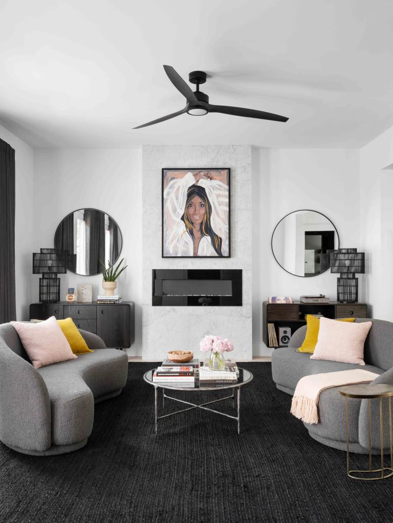 Blush and mustard yellow throw pillows and a cozy blush throw on the stylish sofas add just-the-right hints of color to this sleek and sophisticated living room.