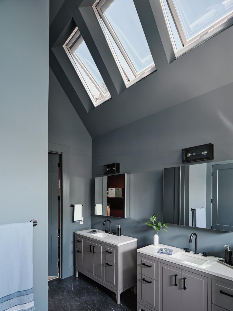 The deep blue gray walls of the primary bathroom give the space a handsome and luxurious quality that still feels open and airy with the added light from the built in skylights.