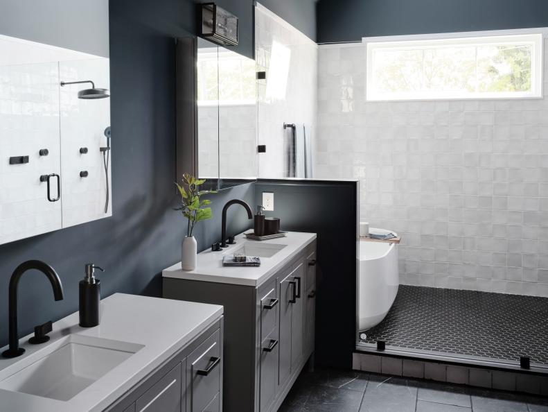 Gray blue walls, white porcelain tile and black accents combine in the primary bathroom to create a luxurious spa-like space that feels clean and modern.