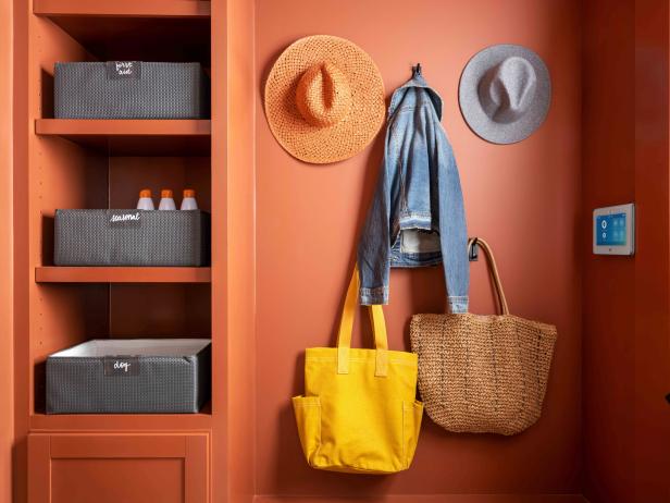 Black stainless hooks on the mudroom wall hold handbags, totes, hats and jackets, keeping these often-used items easily accessible.